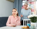 Worried elderly mother reprimanding upset girl at table