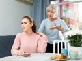 Worried elderly mother reprimanding upset girl at table