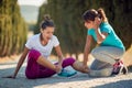 Worried female comfort other one with injured ankle Royalty Free Stock Photo