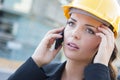 Worried Female Contractor Wearing Hard Hat on Site Using Phone Royalty Free Stock Photo