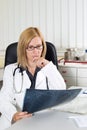 Worried Female Doctor Examining X-ray of a Patient in Consulting Room