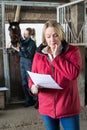 Worried Female Horse Owner Looking At Bill From Vet