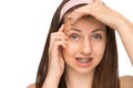 Worried girl with braces squeezing pimple isolated