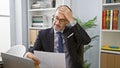 Worried grey-haired middle age man reading critical business document in office, engrossed in deep thought Royalty Free Stock Photo