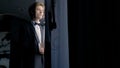 A worried groom man standing by the window. Action. Thoughtful attractive husband wearing suit before wedding ceremony.