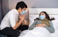 Worried husband take care his sick wife while she sleeping on bed at home, people must  be wearing medical mask protecting from Royalty Free Stock Photo