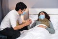 Worried husband take care his sick wife while she sleeping on bed at home, people must  be wearing medical mask protecting from Royalty Free Stock Photo