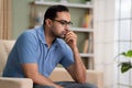 Worried indian man in deep thinking while sitting on sofa at home - concept of financial problem, love breakup and Royalty Free Stock Photo