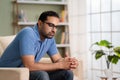 Worried indian man in deep thinking while sitting on sofa at home - concept of financial problem, love breakup and Royalty Free Stock Photo