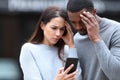 Worried interracial couple checking phone in the street Royalty Free Stock Photo