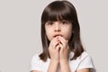 Worried about left alone little girl holding hands near mouth. Royalty Free Stock Photo