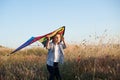 Worried little caucasian boy with kite looking up in dry yellow summer field with blue sky on background Royalty Free Stock Photo