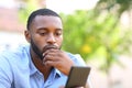 Worried man with black skin checking mobile phone in a park Royalty Free Stock Photo