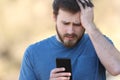 Worried man checking smartphone outdoors Royalty Free Stock Photo