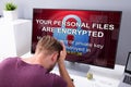 Worried Man At Computer With Ransomware On The Screen