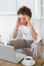 Worried man with head in hands looking at laptop at home Royalty Free Stock Photo