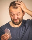 Worried man looking at little mirror