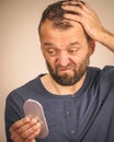 Worried man looking at little mirror