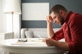 Worried man reading paper letter at white table in room Royalty Free Stock Photo