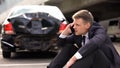 Worried man talking on phone outdoors broken auto background, traffic collision