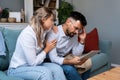 Worried man and woman husband and wife business owners looking tablet statistics feeling disappointed bank account negative