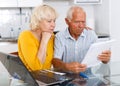 Worried mature couple with documents near laptop in home Royalty Free Stock Photo