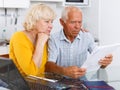 Worried mature couple with documents near laptop in home Royalty Free Stock Photo