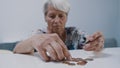 Worried mature gray haired woman counting coins. Low pension concept