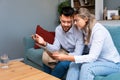 Worried man and woman husband and wife business owners looking tablet statistics feeling disappointed bank account negative