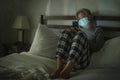 Worried middle aged woman 50s with grey hair and protective mask checking online news with mobile phone during covid-19 virus home Royalty Free Stock Photo