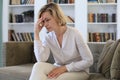 Worried middle aged woman sitting on a sofa in the living room Royalty Free Stock Photo