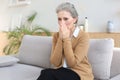 Worried middle aged woman sitting on a sofa in the living room Royalty Free Stock Photo