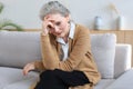 Worried middle aged woman sitting on a sofa in the living room Royalty Free Stock Photo