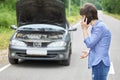 Worried woman talks on the phone near her old broken car on the road Royalty Free Stock Photo