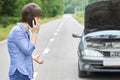 Worried woman talks on the phone near her old broken car on the road Royalty Free Stock Photo