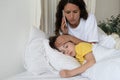 Worried mother call to doctor checking temperature of sick kid lying in bed. Child cure and health Royalty Free Stock Photo