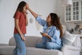 Worried mother holding phone touching forehead of sick daughter, calling to doctor pediatrician Royalty Free Stock Photo