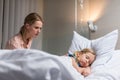 worried mother looking at sick kid sleeping on bed Royalty Free Stock Photo