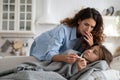 Worried mother looking at thermometer checking temperature of sick child daughter lying in bed Royalty Free Stock Photo