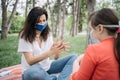 Worried mother rubbing her hands with sanitizer while sitting in park