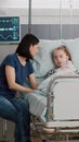 Worried mother sitting beside sick daughter during sickness examination in hospital ward Royalty Free Stock Photo