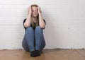 Worried and nervous female sitting against a white brick wall