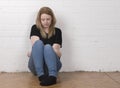 Worried and nervous female sitting against a white brick wall
