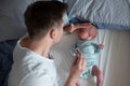 Worried oung father looking on thermometer holding his newborn baby in hands. Royalty Free Stock Photo