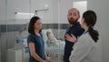 Worried parents discussing sickness recovery treatment with pediatrician doctor in hospital ward