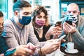 Worried people with face mask checking news on mobile smart phones at coffee break - New normal lifestyle concept with milenials Royalty Free Stock Photo