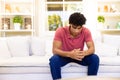 Worried, sad biracial man sitting on sofa in living room thinking, copy space Royalty Free Stock Photo