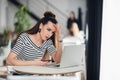 Worried and sad woman got bad news from her relatives in a cafe. Puzzled female looking at a laptop and holding phone. Royalty Free Stock Photo