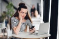 Worried and sad woman got bad news from her relatives in a cafe. Puzzled female looking at a laptop and holding phone. Royalty Free Stock Photo