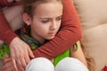 Worried and sad young girl sitting on sofa - woman embracing and comforting her